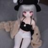 DD096 Luna 85cm TPE doll, seated pose in black top and white shorts, highlighting her petite body and faux-fur jacket.